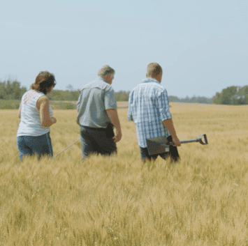 Three People Walking Through Field